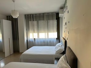 A room with a bed, a wardrobe, and a window with curtains. - Two-Bedroom Family Apartment (Venezia)