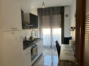 A compact kitchen with a gas stove, oven, and modern cabinetry. - Two-Bedroom Family Apartment (Venezia)