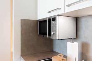 Una cocina compacta con microondas, dispensador de toallas de papel y una caja de cartón sobre la encimera.