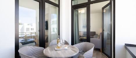 Ein Balkon mit Tisch, Stühlen, einer Flasche und Gläsern.