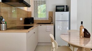 A compact kitchen with a microwave, refrigerator, and a small dining table with a chair. - ALBIZIA Residence: 1-Bedroom Apartment with Spa, Pool, and Parking - Renovated in 2026 (Gréoux-les-Bains)