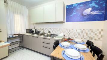 Una cocina moderna equipada con microondas, hervidor y un comedor para cuatro personas, con platos y cubiertos.
