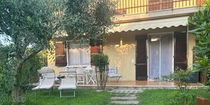 A two-story building with a balcony, outdoor seating area with chairs and a table, and a small garden with a tree and a lawn. - Sirmione Brema Wave House with Garden—Near the Lake (Sirmione)