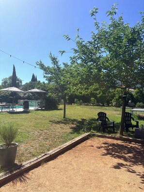 Un patio trasero con piscina, muebles de exterior y un árbol.