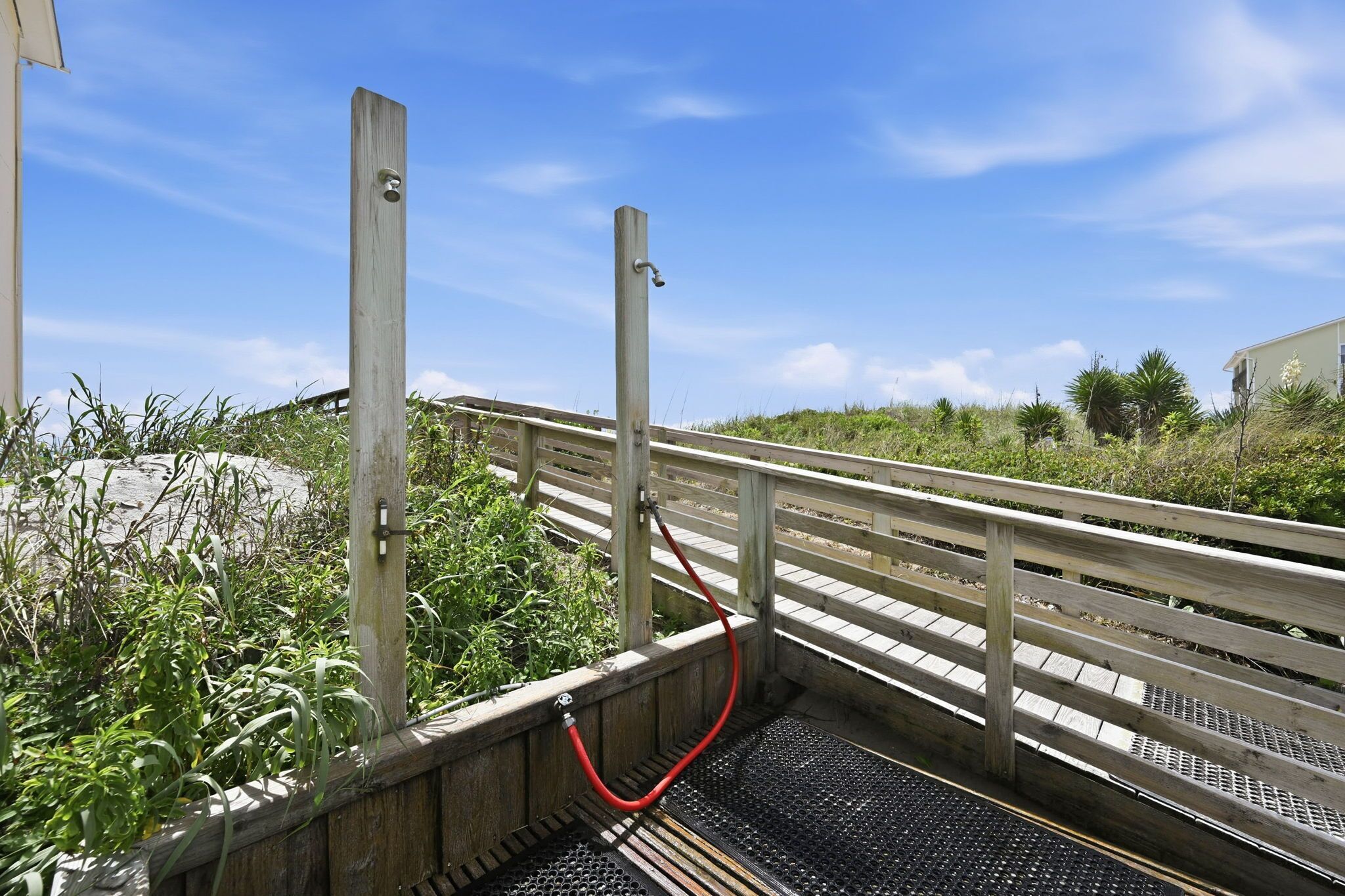 A wooden bridge with metal railings and a red hose on a concrete path.
