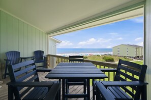 A covered outdoor seating area with a view of the beach and ocean. - A Sea View: Modern Coastal Luxury | 2BR/2BA with Ocean Views (Surf City)