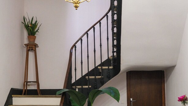 Eine Treppe mit einem Chandelier, einem Blumentopf, einem Klavier und einer Tür.