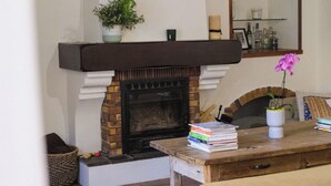 Ein Wohnzimmer mit Kamin, einer Couch, einem Tisch mit Büchern und einem Spiegel an der Wand.