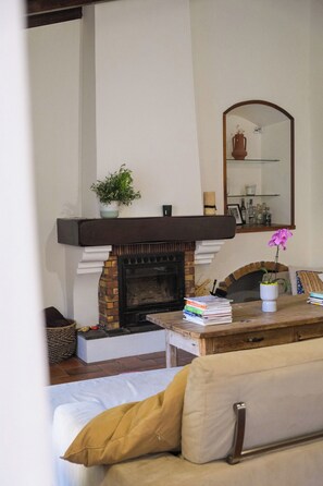 Ein Wohnzimmer mit Kamin, einer Couch, einem Tisch mit Büchern und einem Spiegel an der Wand.