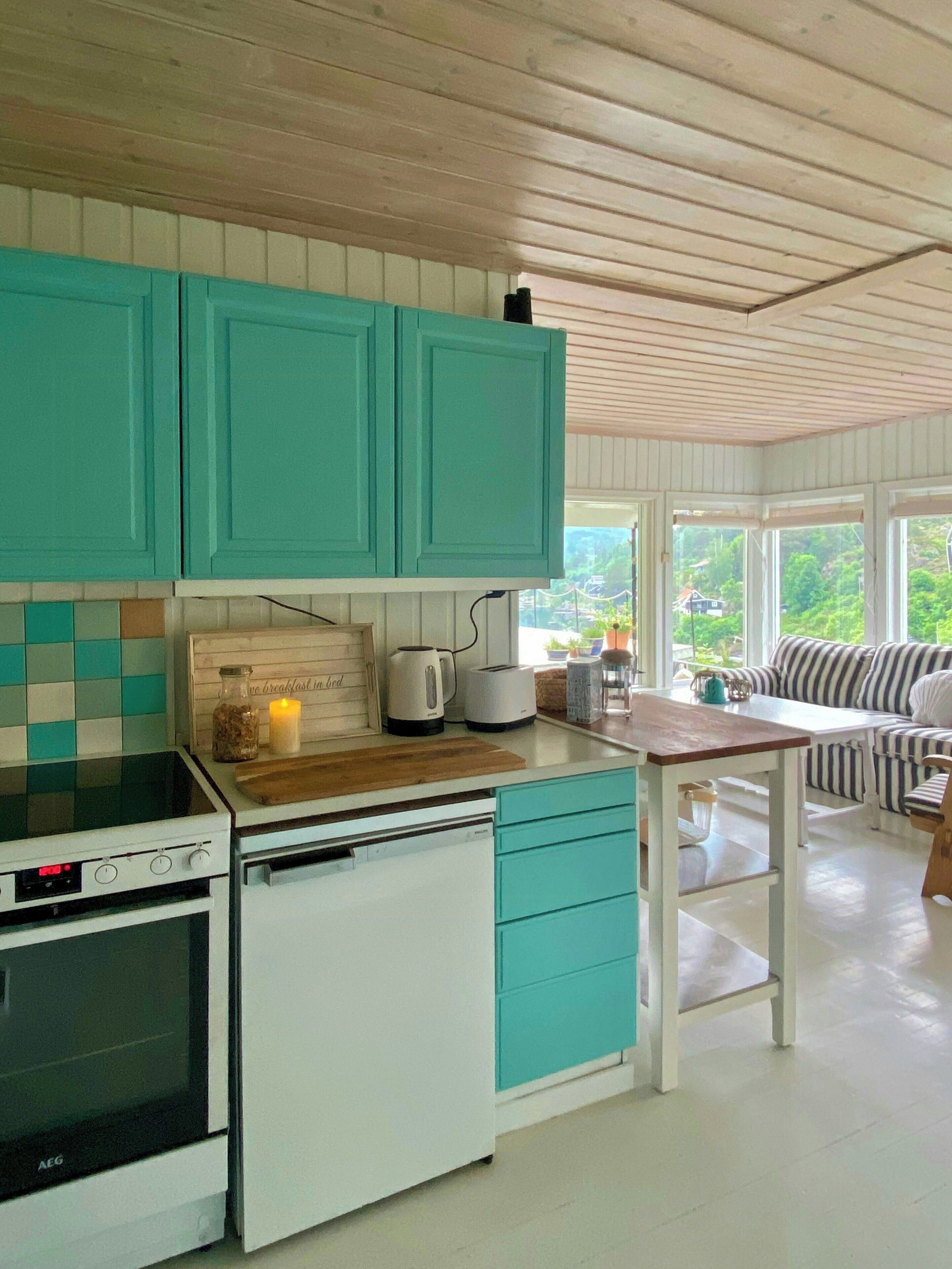 Een keuken met blauwgroene kastjes, een witte kookplaat en een houten aanrecht.