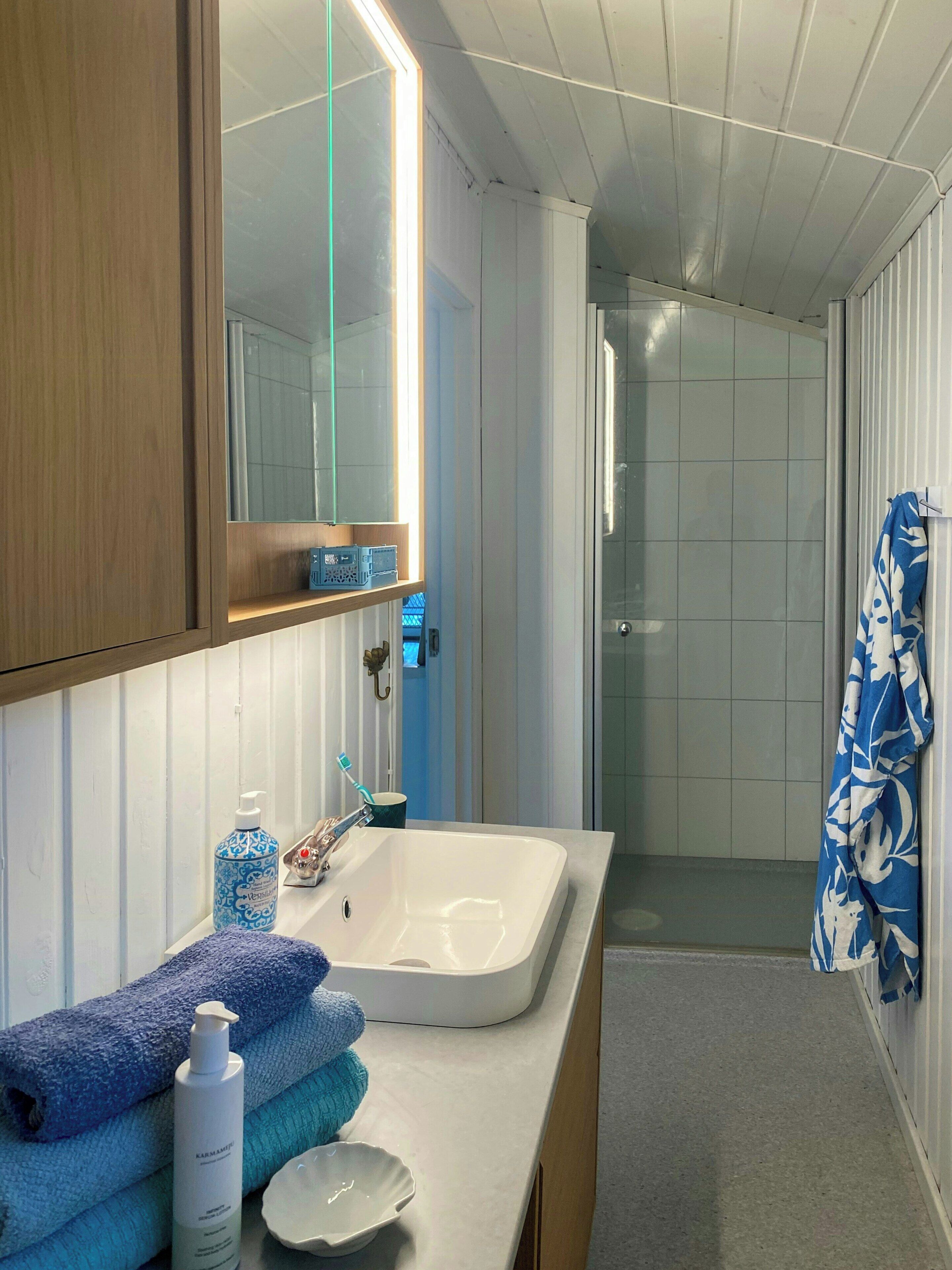 A bathroom with a white sink, a mirror, and a shower area.