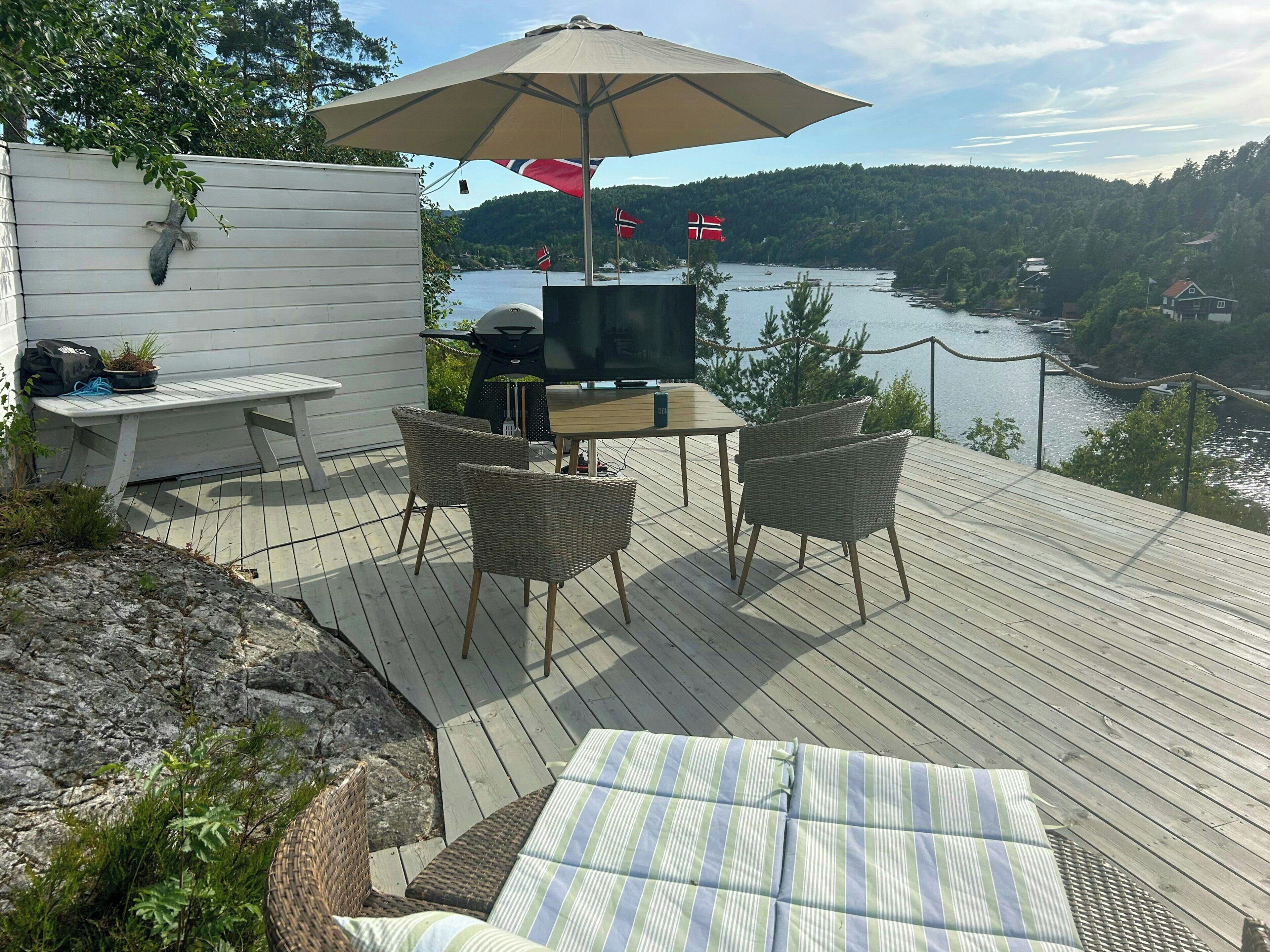 An outdoor deck with a table and chairs, a grill, and a TV.