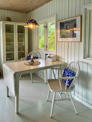 A dining area with a table, chairs, a radio, and a cabinet with glass doors.
