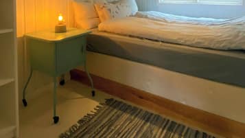 Ein Schlafzimmer mit Bett, Nachttisch, Lampe, Fenster und Teppich.