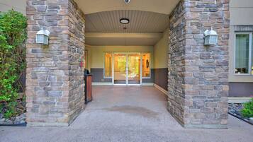A stone entrance with glass doors, a security camera, and a fire alarm.