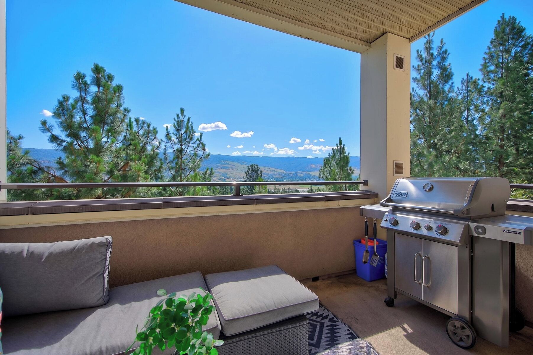 A balcony with a grill, a sofa, and a view of mountains.