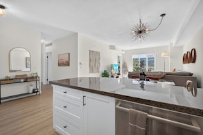 A modern kitchen with a granite countertop, white cabinetry, and a stainless steel dishwasher. - Mountain View 2318 w Pool Hot-tub and Golf (Kelowna)