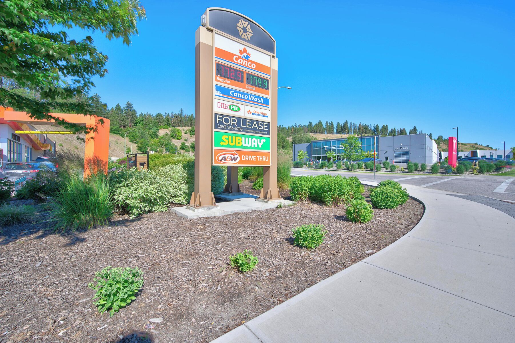 A commercial area with a large signboard advertising various services including a Subway, a drive-thru, and a for lease sign.