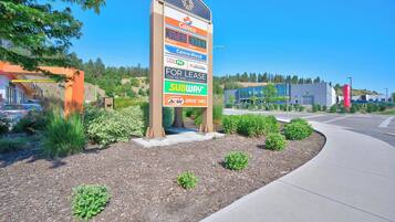 A commercial area with a large signboard advertising various services including a Subway, a drive-thru, and a for lease sign.
