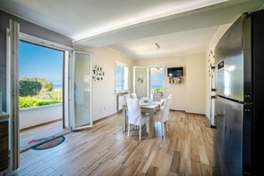 A modern kitchen with a built-in refrigerator, a dining area with a table and chairs, and a sliding glass door leading to a balcony with a view. - Sunlit gulffront villa with pool (Carini)