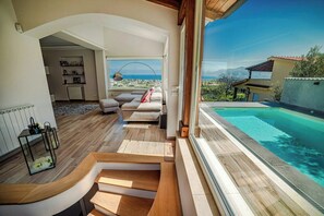 A modern living room with a view of a swimming pool and mountains. - Sunlit gulffront villa with pool (Carini)
