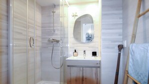 A bathroom with a glass-enclosed shower, a wooden vanity, and a mirror above the sink. - 1 bedroom lovely apartment in Théoule sur Mer (Théoule sur Mer)