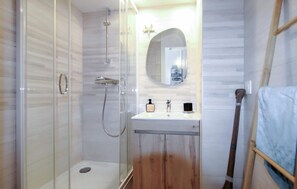 A bathroom with a glass-enclosed shower, a wooden vanity, and a mirror above the sink. - 1 bedroom lovely apartment in Théoule sur Mer (Théoule sur Mer)