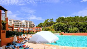 A hotel pool area with sun loungers, umbrellas, and a building with multiple balconies. - 1 bedroom lovely apartment in Théoule sur Mer (Théoule sur Mer)