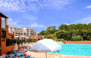 A hotel pool area with sun loungers, umbrellas, and a building with multiple balconies. - 1 bedroom lovely apartment in Théoule sur Mer (Théoule sur Mer)