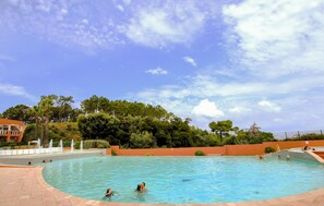 A swimming pool with people in it, surrounded by trees and a clear sky. - 1 bedroom lovely apartment in Théoule sur Mer (Théoule sur Mer)