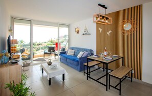 A modern living room with a blue sofa, a dining table set for two, and a balcony with a view. - 1 bedroom lovely apartment in Théoule sur Mer (Théoule sur Mer)