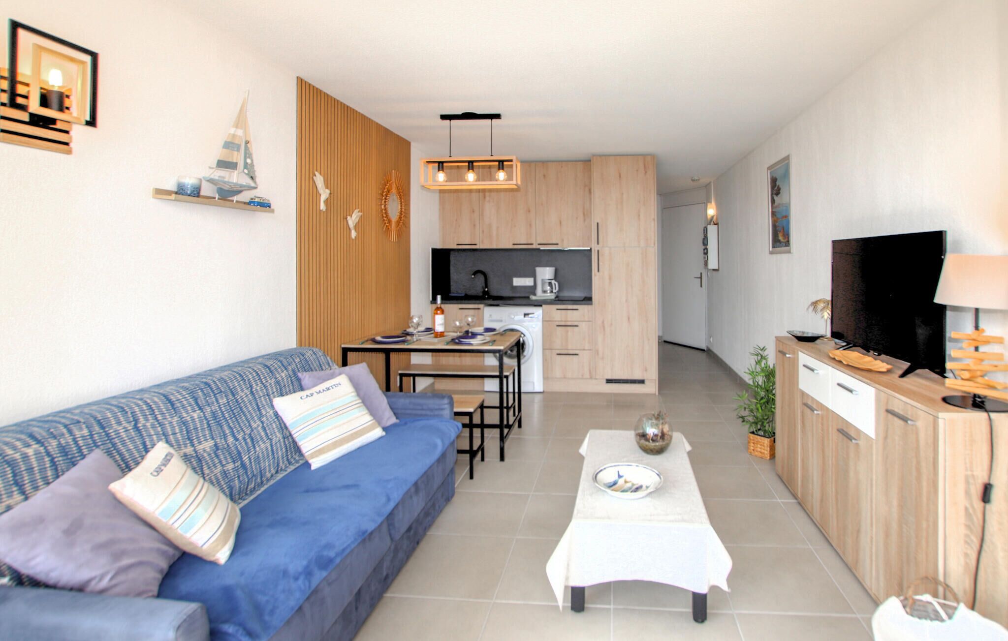 A modern living room with a sofa, a dining table, and a kitchen in the background.
