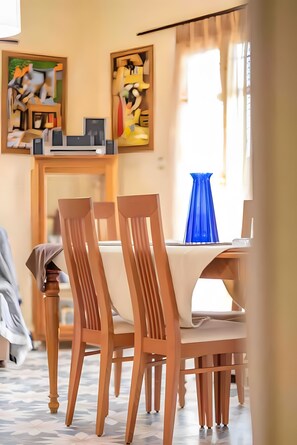 Un coin repas avec des chaises en bois, une table et des œuvres d’art accrochées au mur.