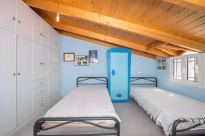 A bedroom with two beds, a wardrobe, and a ceiling with wooden beams. - Hillside Hideaway mountain villa with views, shared terrace, and private garden (Skiadas)