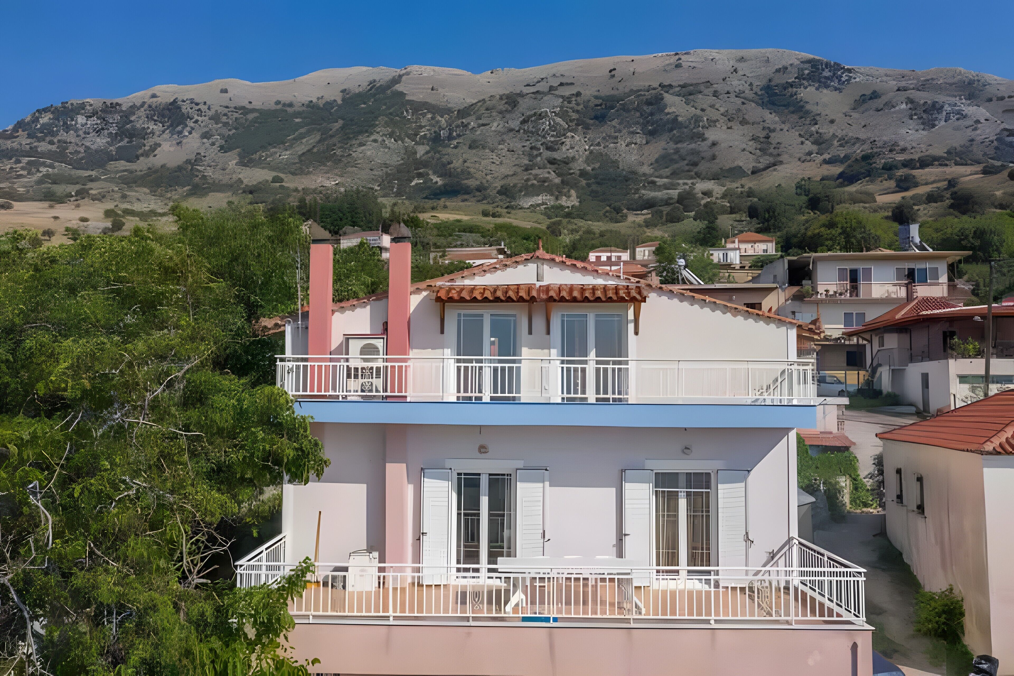 A two-story building with a balcony, a chimney, and a view of a mountainous landscape.