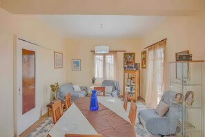 A spacious living room with a large dining table, comfortable seating, and a bookshelf.