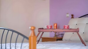Ein Bett mit Kopfteil, ein Nachttisch mit Kerze und ein Tablett mit zwei Tassen.