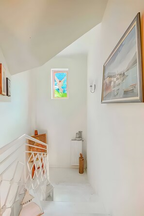 A narrow stairway with a white railing, a framed picture on the wall, and a radiator on the floor. - Hillside Hideaway mountain villa with views, shared terrace, and private garden (Skiadas)