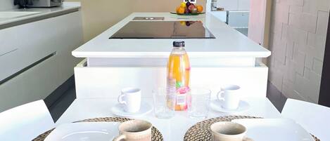 A modern kitchen with a flat-screen TV, a microwave, and a fruit bowl on the counter.