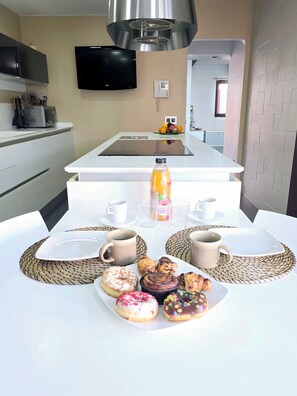 A modern kitchen with a flat-screen TV, a microwave, and a fruit bowl on the counter. - Oasis House (Maspalomas)