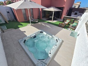 Ein Whirlpool mit Terrasse, Sitzgelegenheiten im Freien und Blick auf die umliegenden Gebäude.