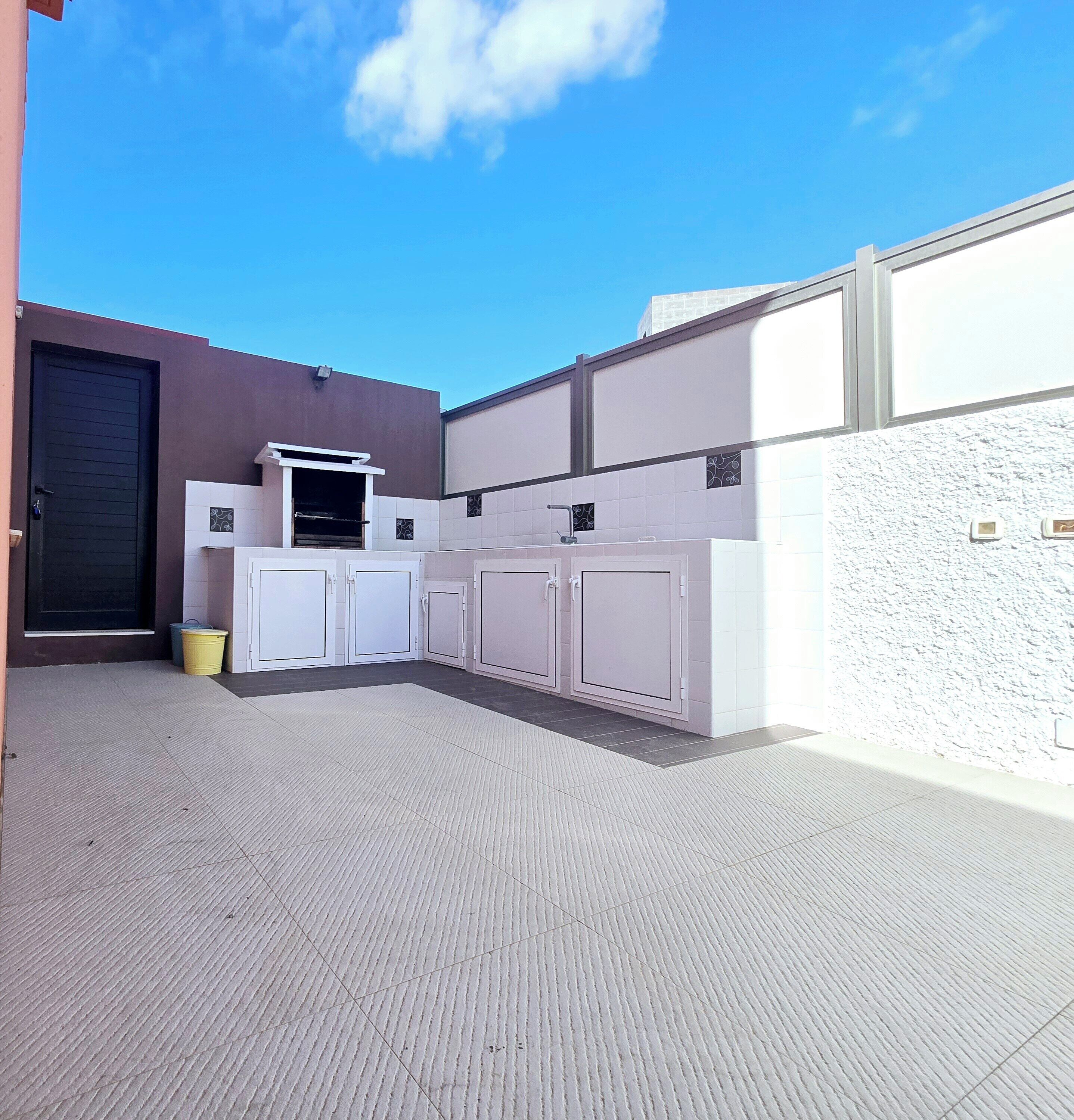 A compact outdoor kitchen area with a built-in oven, a sink, and a small window.