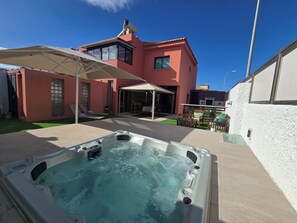 A hot tub in a backyard with a house in the background. - Oasis House (Maspalomas)