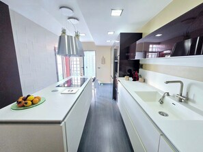 A modern kitchen with a central island, built-in appliances, and a view to the outside. - Oasis House (Maspalomas)