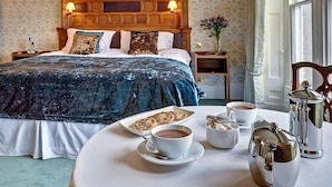 Quarto de hotel com uma cama grande, uma mesa redonda com itens de café da manhã e vista para o exterior.
