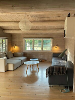 A cozy living room with a wooden ceiling, a round table, and two sofas. - Beamed house by the water in Hornbæk (Hornbæk)