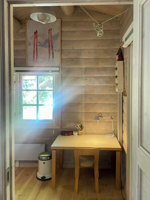 A wooden-paneled room with a table, a chair, a window, and a radiator. - Beamed house by the water in Hornbæk (Hornbæk)