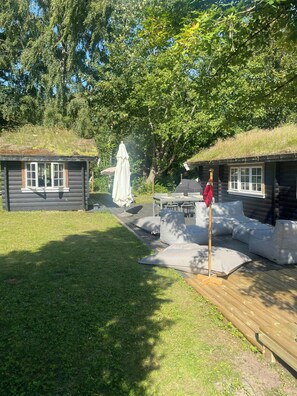 A log cabin with a grassy roof, a dining area with outdoor seating, and a small garden area. - Beamed house by the water in Hornbæk (Hornbæk)