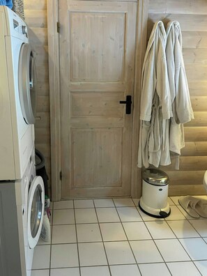 A laundry area with a washing machine, a wooden door, and towels hanging on the wall. - Beamed house by the water in Hornbæk (Hornbæk)