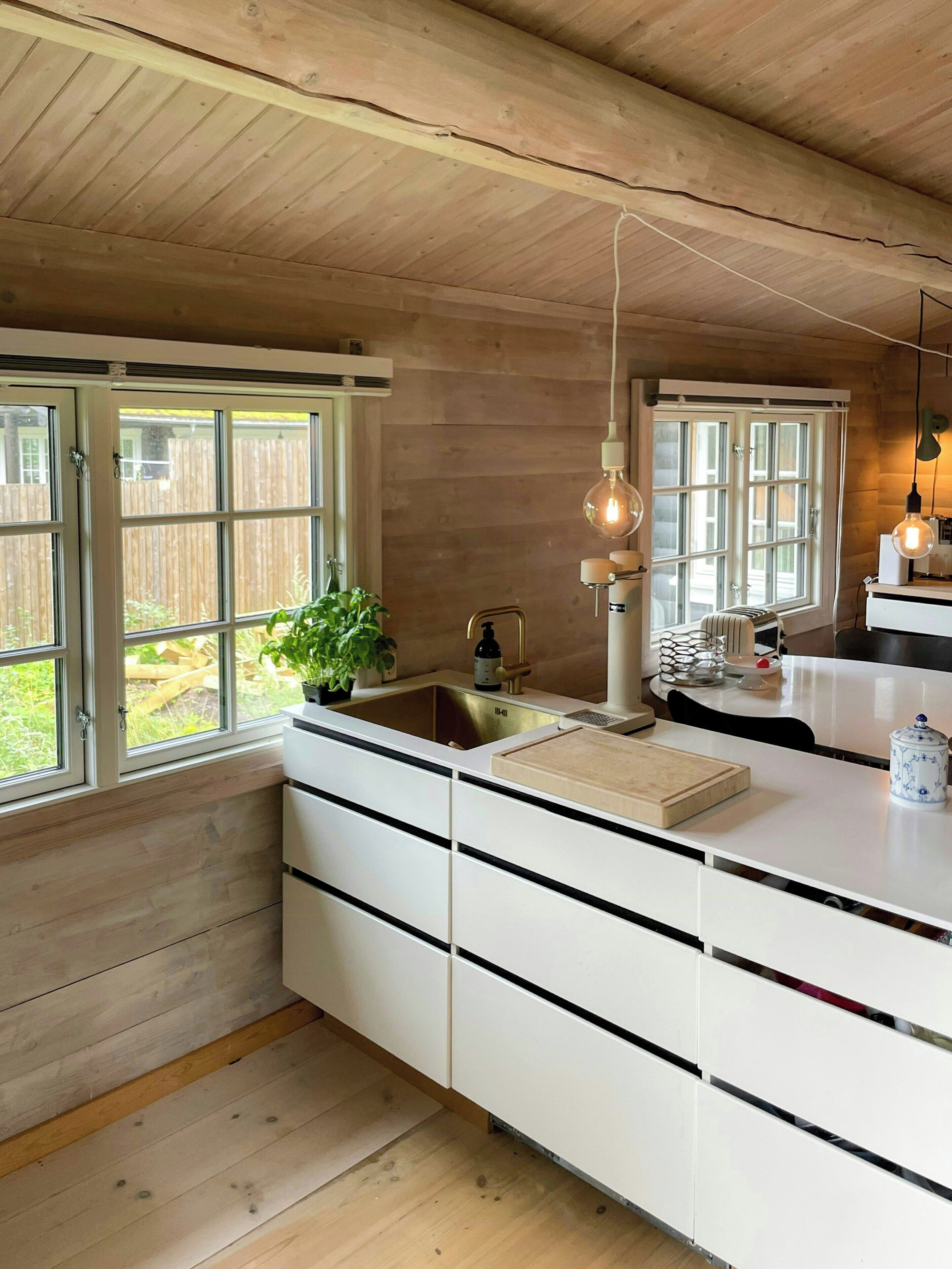 Una cocina moderna con vigas de madera, una isla grande con un lavamanos e iluminación colgante.